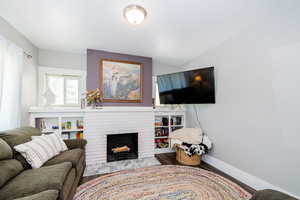 Living area with wood finished floors, a brick fireplace, and baseboards