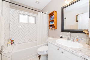 Bathroom with toilet, vanity, and shower / bath combo