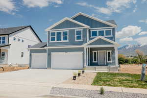 View of front of house with board and batten siding, a mountain view, driveway, a porch, and a garage