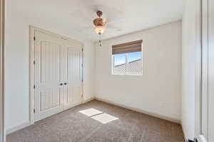 Unfurnished bedroom featuring light carpet, a closet, baseboards, and ceiling fan