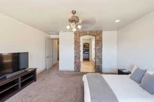 Carpeted bedroom featuring arched walkways, baseboards, and ceiling fan