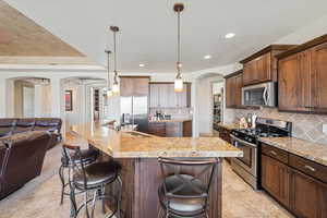 Kitchen featuring stainless steel appliances, arched walkways, a sink, open floor plan, and a breakfast bar