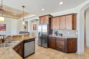 Kitchen featuring stainless steel appliances, a sink, arched walkways, backsplash, and hanging light fixtures
