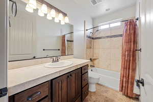 Bathroom with shower / bathtub combination with curtain, toilet, and vanity