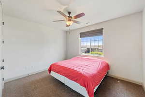 Carpeted bedroom featuring baseboards and ceiling fan