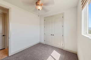 Unfurnished bedroom with carpet flooring, a closet, a ceiling fan, and baseboards
