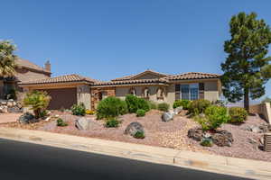 Mediterranean / spanish home with stucco siding, an attached garage, and a tiled roof