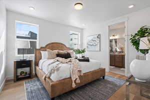 Bedroom featuring light wood-style floors, ensuite bathroom, recessed lighting, and baseboards