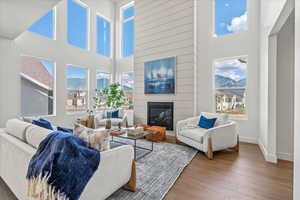Living room with plenty of natural light, wood finished floors, a high ceiling, a fireplace, and baseboards