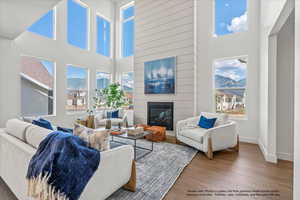 Living room with a mountain view, a fireplace, wood finished floors, and a high ceiling