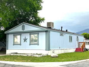 View of side of home with a mountain view, a lawn, and central air condition unit