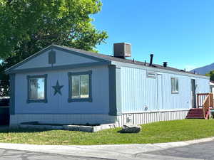 View of side of property featuring a yard and central AC