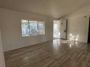 Empty room with vaulted ceiling and wood finished floors