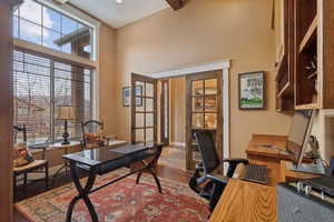 Home office featuring a high ceiling, french doors, and baseboards