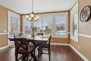 Dining area with a chandelier, dark wood finished floors, and baseboards