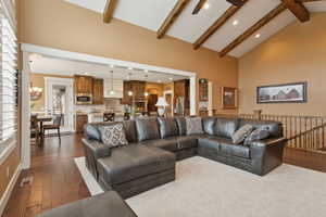 Living area featuring a chandelier, high vaulted ceiling, dark wood-type flooring, recessed lighting, and beamed ceiling