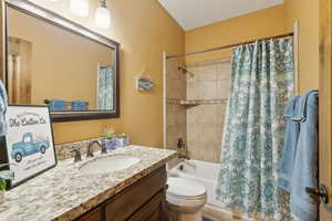 Full bathroom featuring shower / tub combo with curtain, vanity, and toilet