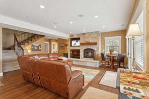 Living area featuring a fireplace, stairway, wood finished floors, and recessed lighting