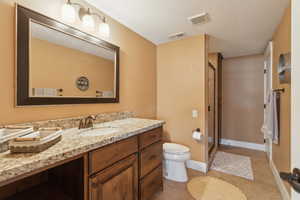 Bathroom featuring toilet, vanity, a shower stall, tile patterned flooring, and baseboards