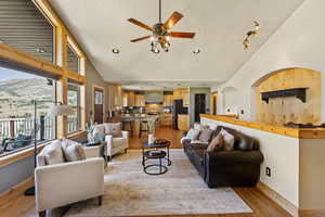 Living area with light wood-style floors, a textured ceiling, ceiling fan, a mountain view, and high vaulted ceiling