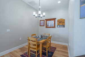 Dining room with a chandelier, light wood-style floors, baseboards, and recessed lighting
