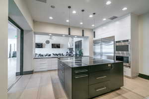 Kitchen featuring stainless steel appliances, dark countertops, modern cabinets, white cabinets, and a kitchen island