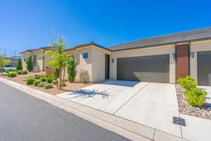 View of front of property featuring driveway, stucco siding, a tile roof, and an attached garage