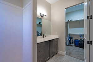Bathroom featuring vanity, tile patterned floors, a spacious closet, and baseboards