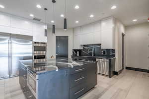 Kitchen featuring built in appliances, modern cabinets, backsplash, white cabinetry, and recessed lighting