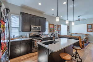 Kitchen featuring stainless steel appliances, a sink, light wood finished floors, a breakfast bar, and recessed lighting