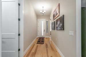 Entryway with light wood-style flooring, a chandelier, and baseboards