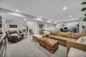 Carpeted living room featuring stairway, recessed lighting, and an office area