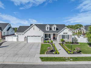 Modern farmhouse style home with board and batten siding, an attached garage, concrete driveway, and stone siding