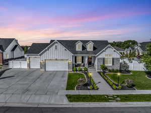 View of front of home featuring board and batten siding, a garage, concrete driveway, and stone siding