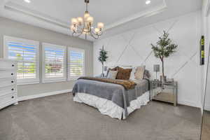 Carpeted bedroom featuring a raised ceiling, a chandelier, baseboards, and recessed lighting