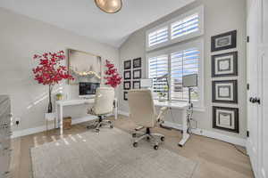 Office featuring wood finished floors, baseboards, and high vaulted ceiling