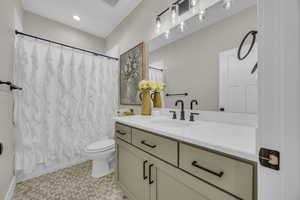 Full bathroom with toilet, vanity, shower / tub combo with curtain, and baseboards