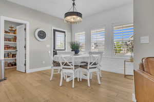 Dining room with a chandelier, light wood-type flooring, and baseboards