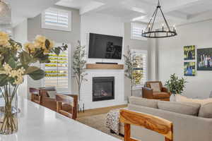 Living area featuring a large fireplace, wood finished floors, beamed ceiling, plenty of natural light, and a chandelier