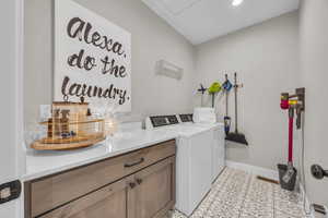 Clothes washing area featuring washer and clothes dryer, baseboards, and recessed lighting