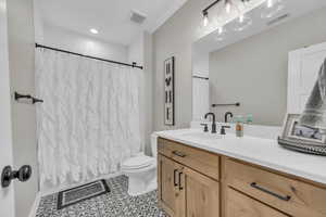 Full bath with toilet, tile patterned flooring, vanity, and shower / bath combo