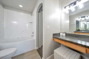 Bathroom featuring wood finished floors, shower / bathtub combination, toilet, baseboards, and vanity