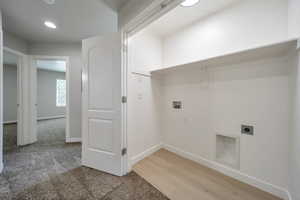 Clothes washing area with hookup for an electric dryer, washer hookup, baseboards, light wood-type flooring, and recessed lighting