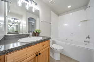 Bathroom featuring bathtub / shower combination, toilet, vanity, and wood finished floors