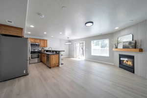 Kitchen featuring stainless steel appliances, a sink, dark countertops, open floor plan, and recessed lighting