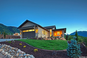 View of front of house featuring a mountain view, a garage, a front lawn, and stone siding