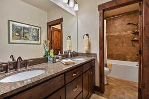 Bathroom featuring toilet, double vanity, and shower / bath combination with curtain