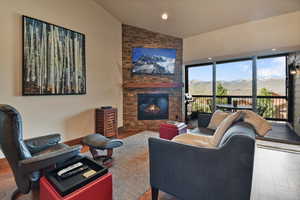 Living area with wood finished floors, a fireplace, and high vaulted ceiling