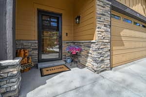 Doorway to property with stone siding and a garage