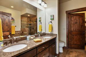 Full bathroom with a tile shower, double vanity, toilet, and tile patterned floors